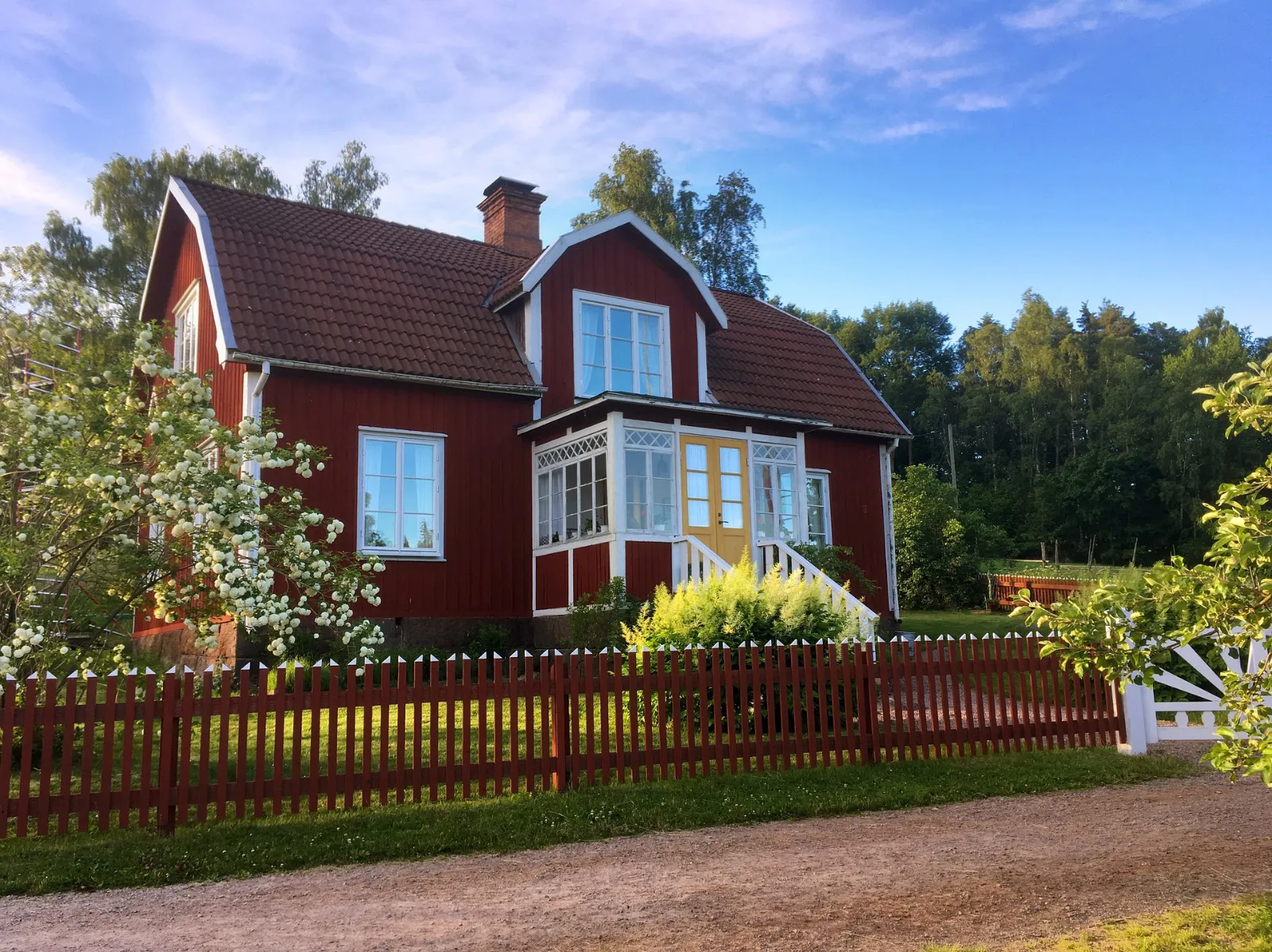 Rött hus i grönskande landsbygdsmiljö.